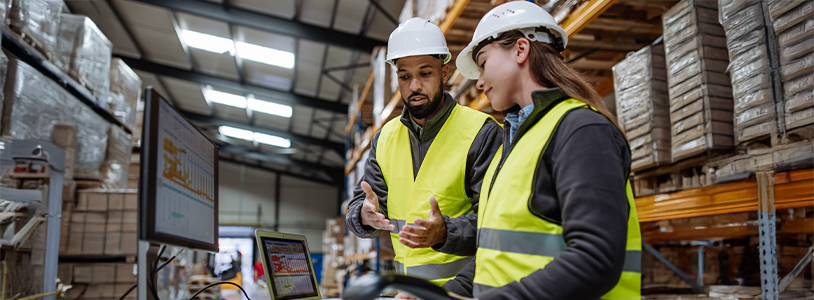 Warehouse Manager Talking With Logistics Employee In Warehouse
